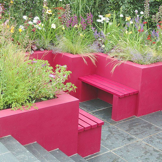 Modern garden with slate flooring and hot pink built-in seats and plant containers