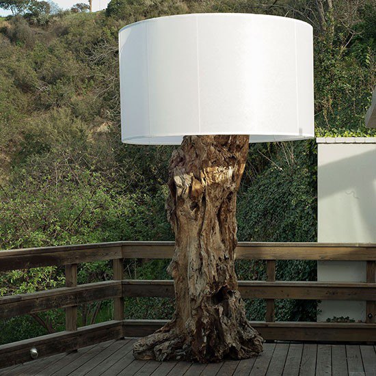 Tree trunk lamp with white lamp shade on wooden decking