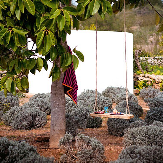 White freestanding garden wall in contemporary garden, with tree swing and striped towel