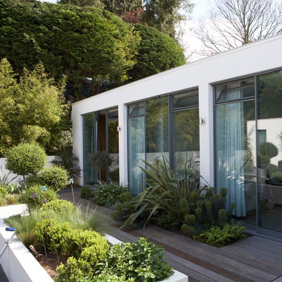 Modernist design decked garden with white planters and glass doors