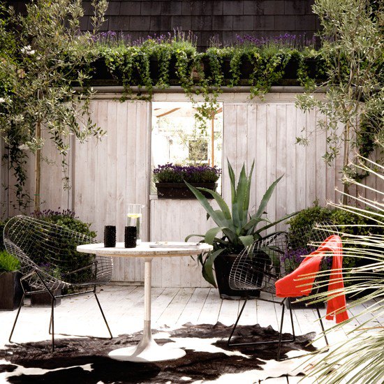 Sunken decked garden with wirework chairs and round table