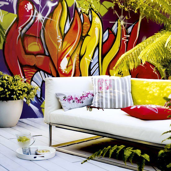 Garden patio with statement wall mural, white sofa and white decking