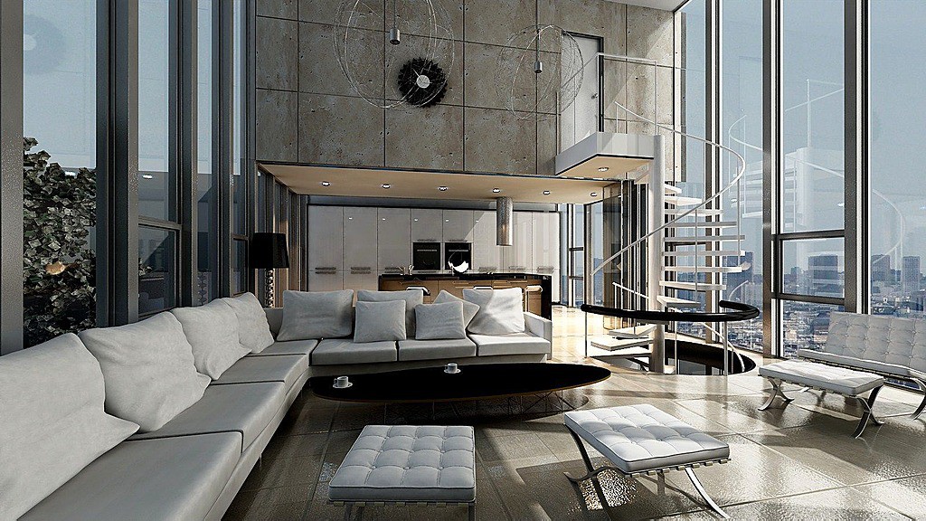 Unique ultra-modern living room design features floor to ceiling glass external walls, metal frame chairs and spiral staircase and kithen area in distance, with grey L-shaped sectional sofa in foreground. Pillow-backed sofa centers around black oval coffee table over textured tile flooring.