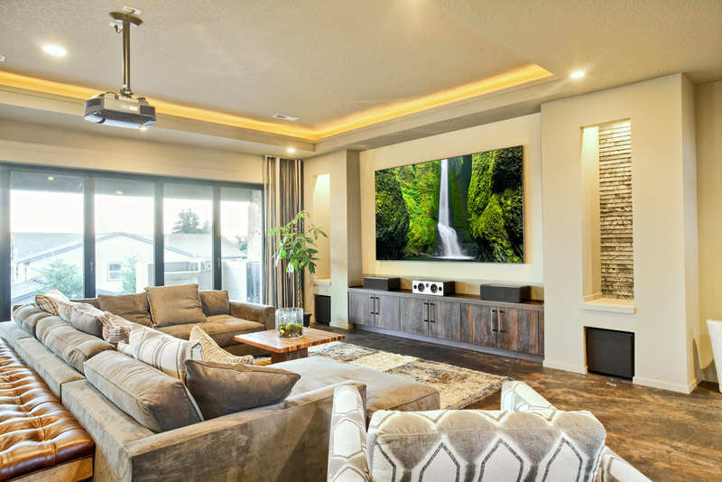 Natural wood media center beneath large projection screen sits across from furniture over shag area rug.