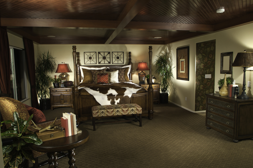 Masculine bedroom design with dark wood ceiling, four poster wood bed and dark brown carpet