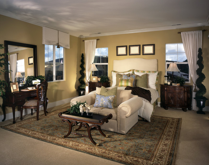 This bedroom uses space well by creating a small sitting area at the end of the bed with a loveseat and coffee table