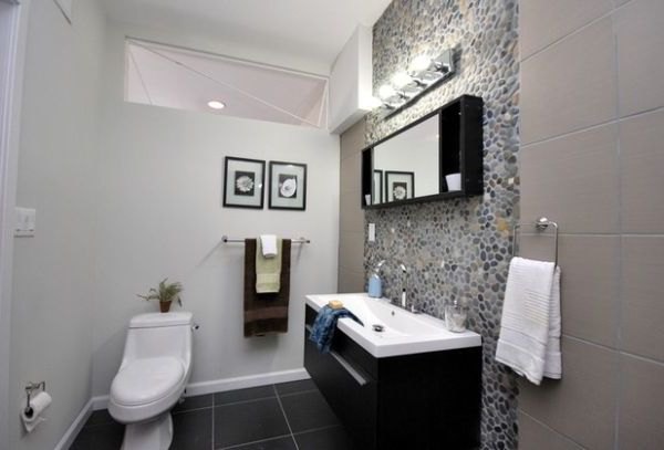Stone tile and sleek floating sink in black form this chic bathroom