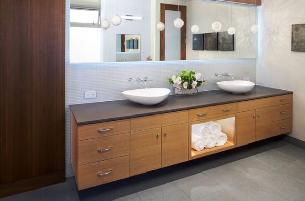 Beautifully back lit mirror atop a gorgeous floating sink in wood