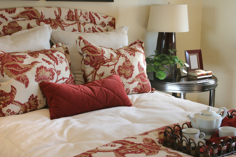 Matching headboard, pillows, and duvet cover are interrupted by blanche pillows and a deep crimson lumbar accent throw pillow.