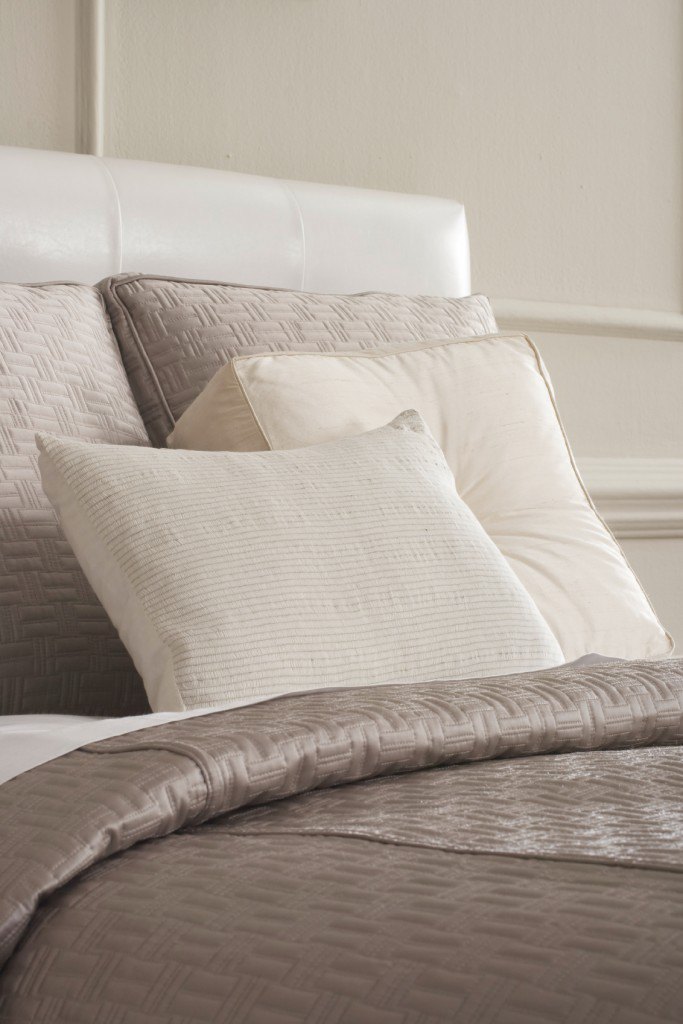 Plush square pillows in complementary neutrals host a lone oblong pillow with subtle striping.
