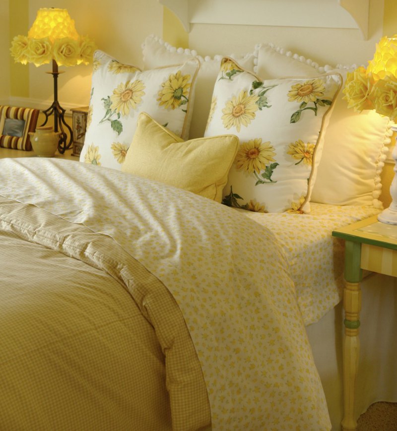 This bright, sunny yellow space is appealing and inviting. Mixing a variety of patterns in coordinating colors, this bedroom area is dynamic and interesting. Rose lampshades in vibrant yellow are a real standout in this lovely and relaxing room.