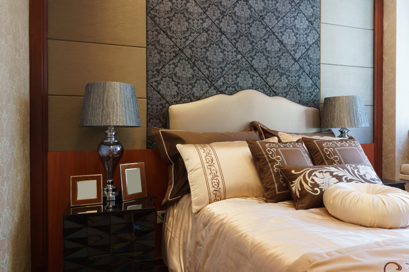 Cream, ivory, and chocolate browns envelop the room, with an intricate black accent panel overseeing the space. An arrangement of delicately embroidered throw pillows grace this lovely bedroom, and offer a richness that would be lacking in their absence.