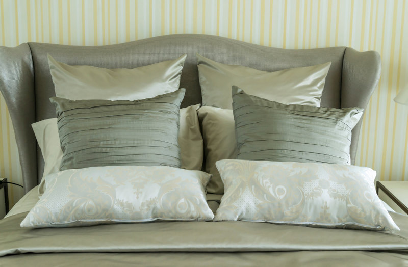 An interesting armed headboard holds a series of square and lumbar throw pillows in a brilliant display of design and symmetry.