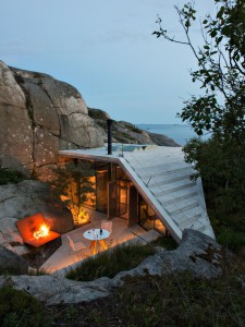 Half-hidden by dense vegetation, this modern cabin is tucked into a rocky Norwegian coastline. It is a 323 sq ft studio design with a sleeping loft suspended from the ceiling. | www.facebook.com/SmallHouseBliss