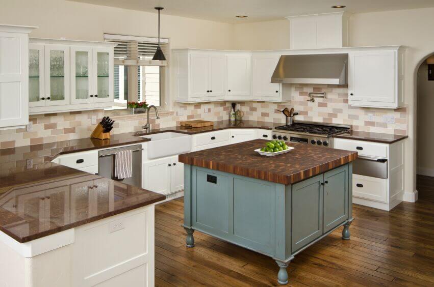 These stunning wood floors are complemented by the island countertop and the chocolate brown granite. The warm palette is continued in the tile backsplash and, in this case, the white cabinets are used to break up the warm tones of the room. Meanwhile, the lovely blue of the island base brings a cool accent color and complements the use of brown.