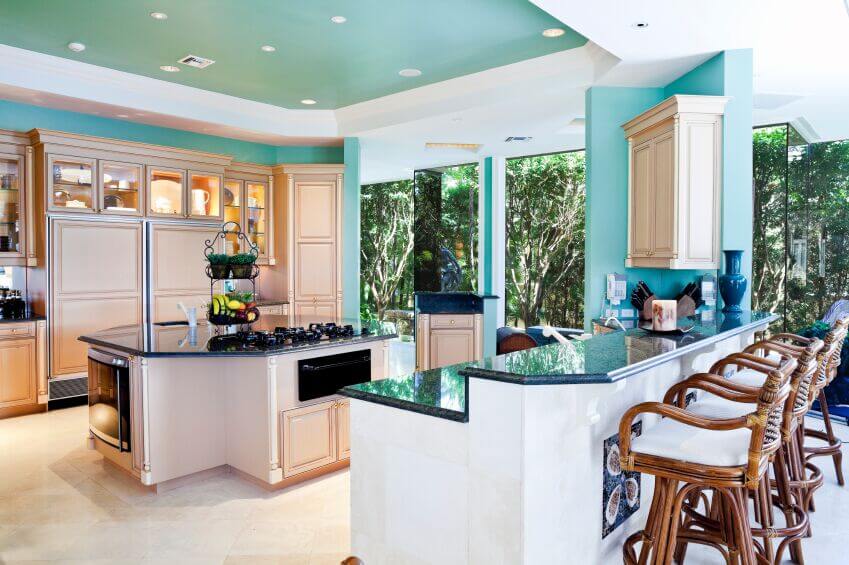 This refreshingly bright kitchen is a fun example of how to use color and keep your kitchen feeling open and inviting. The warm wood cabinets achieve the same light feeling of white cabinets without continuing the same trend. Instead, using white as an accent color in the bar and ceiling makes the room feel larger and doesn\\'t wash everything out.