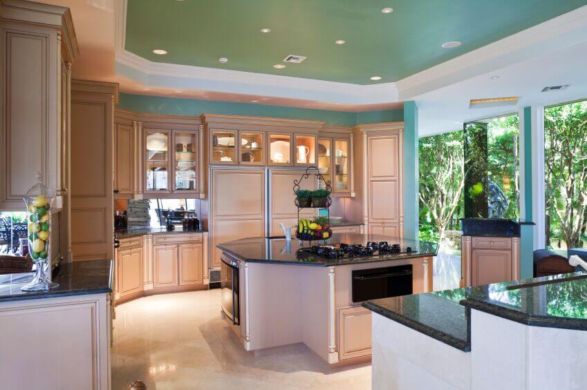 The shape of the dark granite counters mimics the octagonal shape of the island and creates a natural flow around the room. Using the blue wall color in the recessed ceiling while bordering it in white bring interest up to the ceiling without making the room feel smaller or darker.