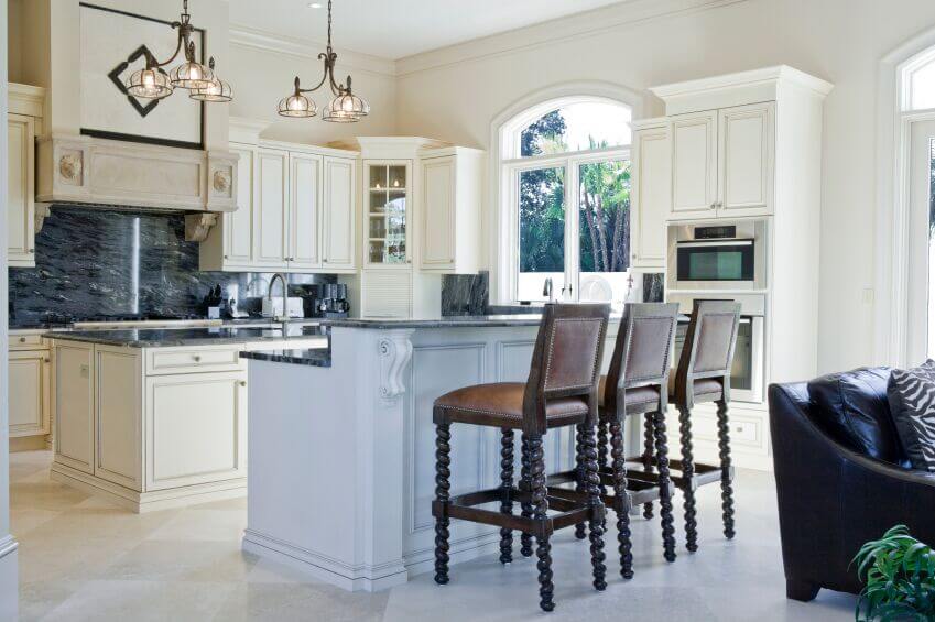 The large windows allow for lots of light to pour in and brighten up the room which in turn highlights the beautiful streaking in the granite counters. Dark wood barstools add functional, warm accents to the room.