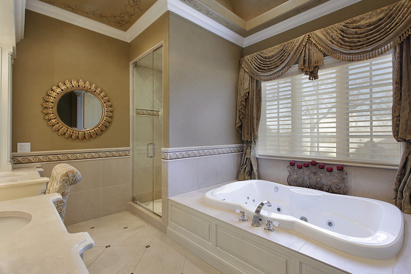 Bathroom uses cream colored ceramic tiles with ceramic tile borders in wave patterns and has an oversized jet tub