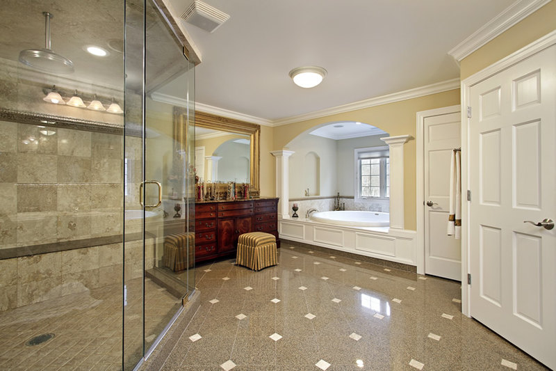 Bathroom is mainly in mocha brown porcelain tiles with cream accents and large tiled rainfall shower