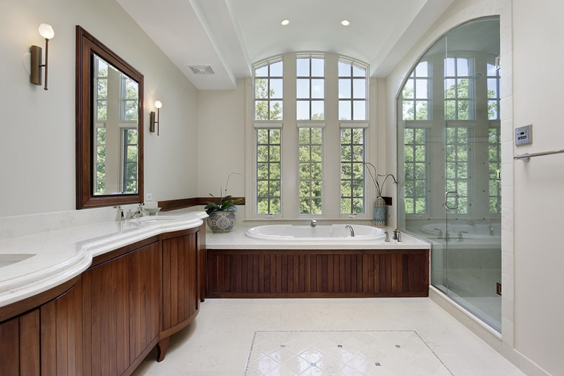 Master bath with vanity using white marble countertops and large glass arched shower
