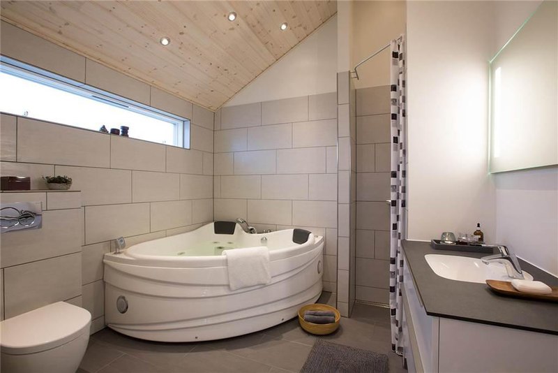 a marvellous grey bathroom with concrete flooring and cedar ceiling with stunning bathtub and simply grey concrete sinks with cornered showering room