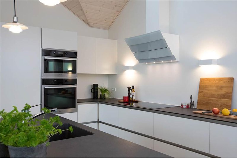a shiny white kitchen cabinet with sohisiticated appliances and simply grey countertops for minimalist kitchen idea with surprising pendant lamps