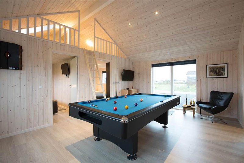 an enchanting billiard table in a cedar wooden hallway with elegant black leather swivel chair and simply table and artful wall decors