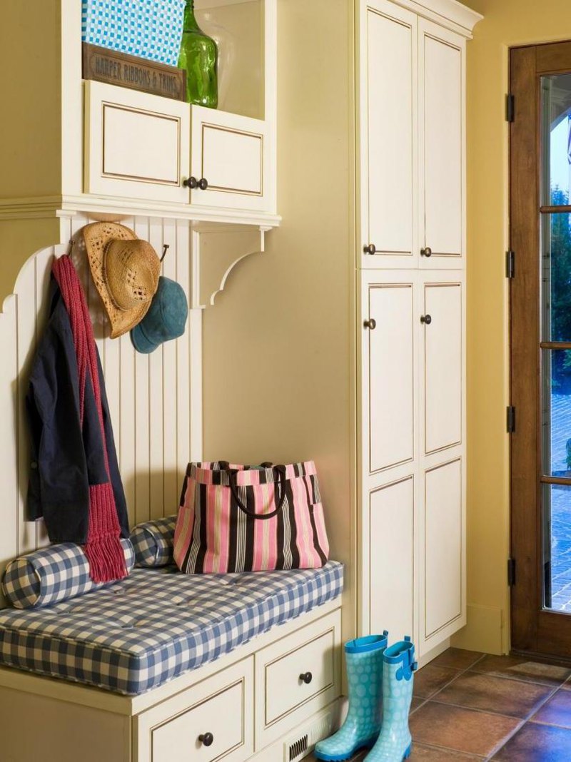 Prett white cupboard with shoe storage bench and few hooks in a small space of a country house hallway