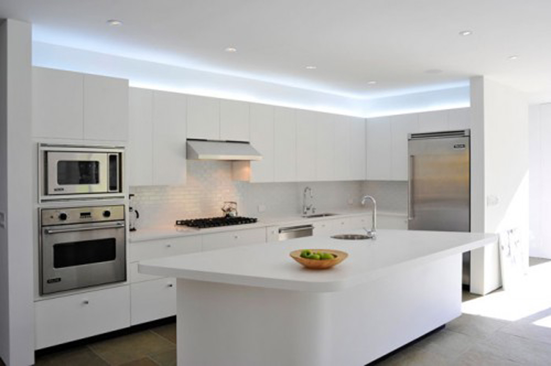 Alluring White LED Lights on Ceiling above White Counter and Floating Cabinets facing Stylish White Island in Minimalist Kitchen Design with Stone Flooring