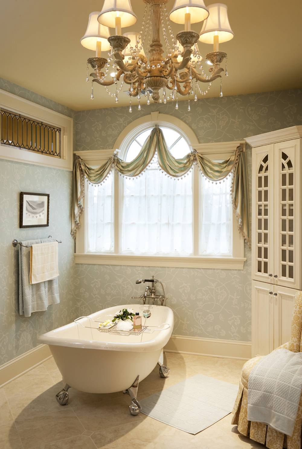 Modest bathroom design in travertine tile flooring featured claw foot bathtub and beautiful chandelier